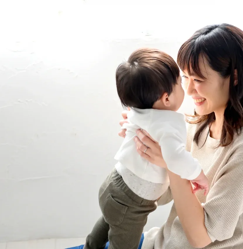 赤ちゃんを抱き上げて微笑む女性