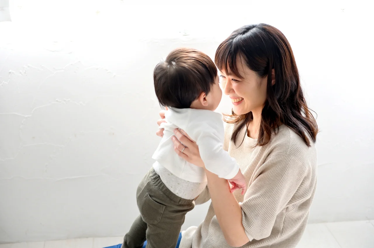 赤ちゃんを抱き上げて微笑む女性